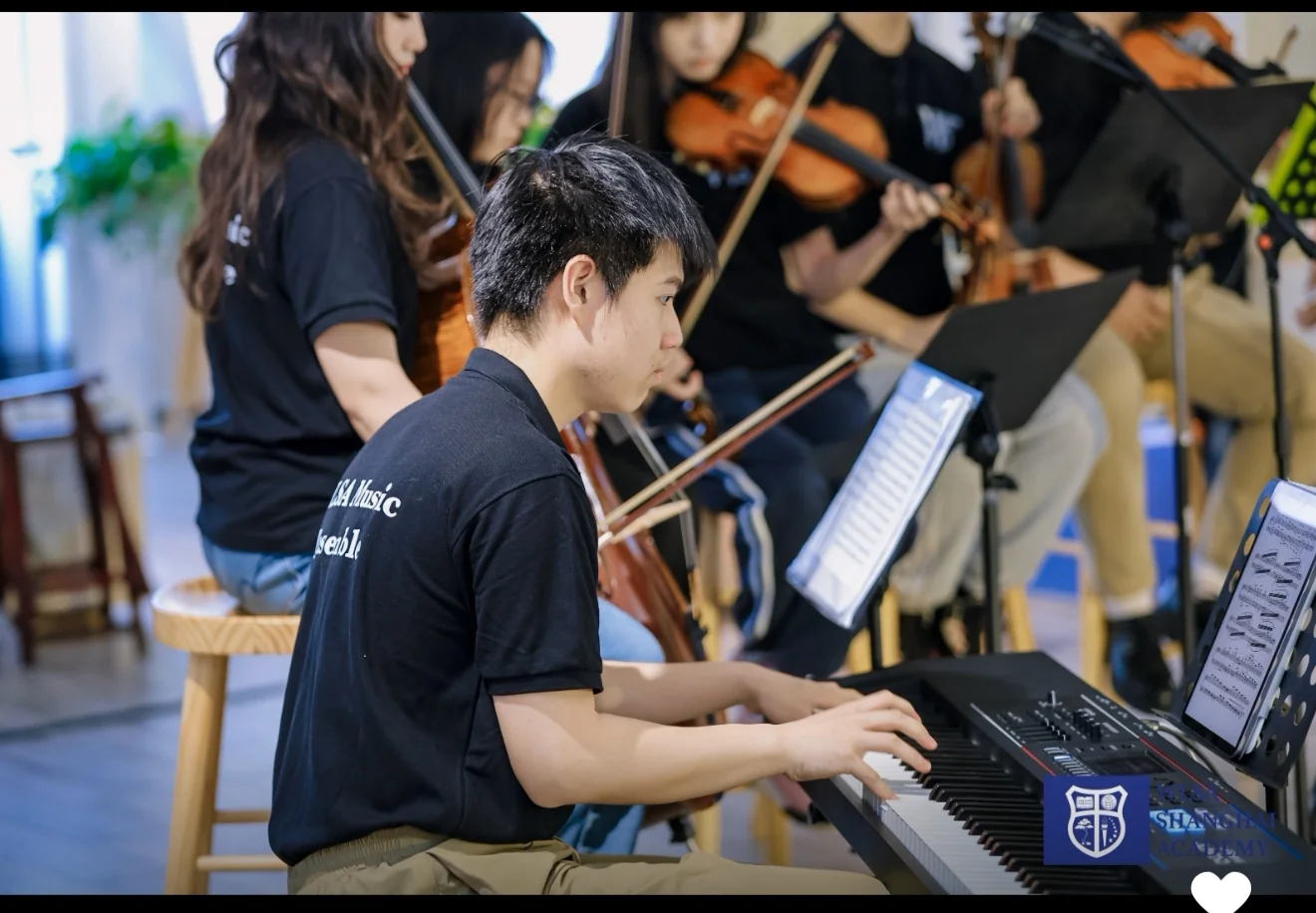Lala playing piano alongside other musicians in an ensemble